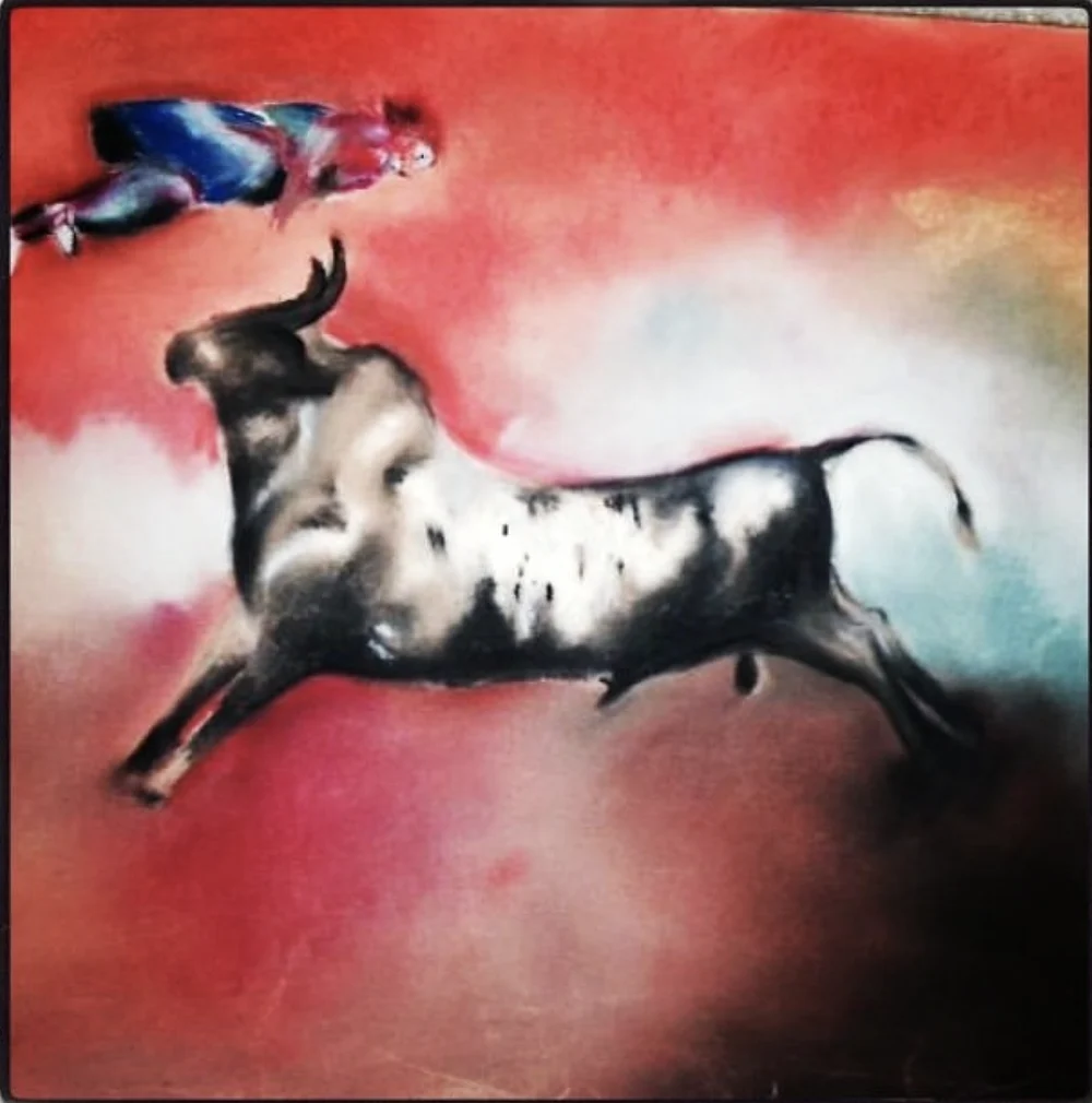 A painting of a leaping black and white bull with a falling matador above it, on a red ground