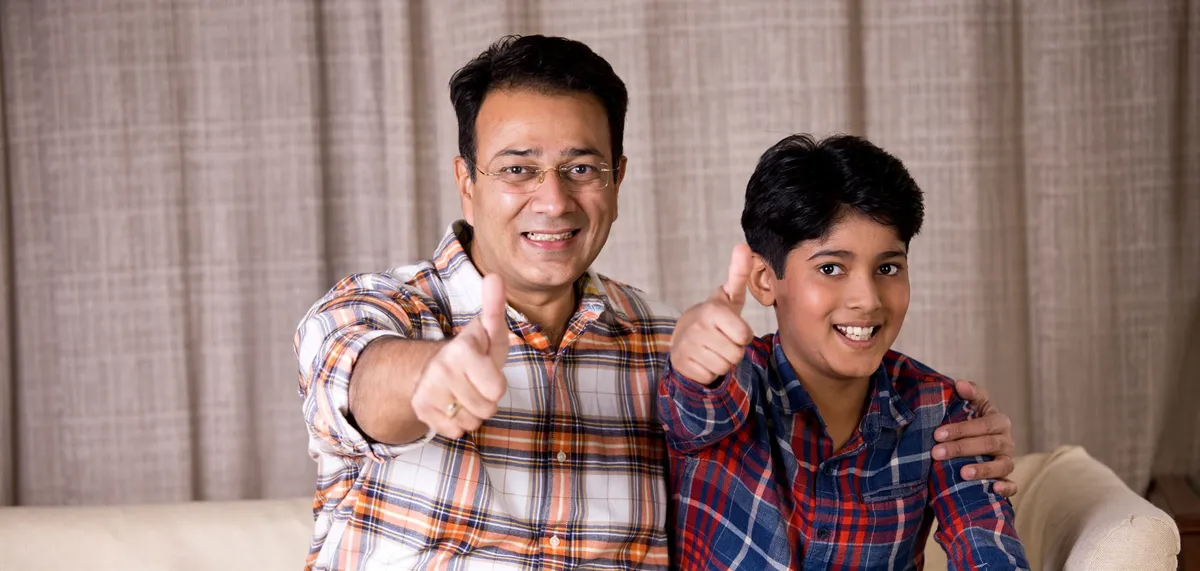 A father and his teenage son giving a thumbs up together