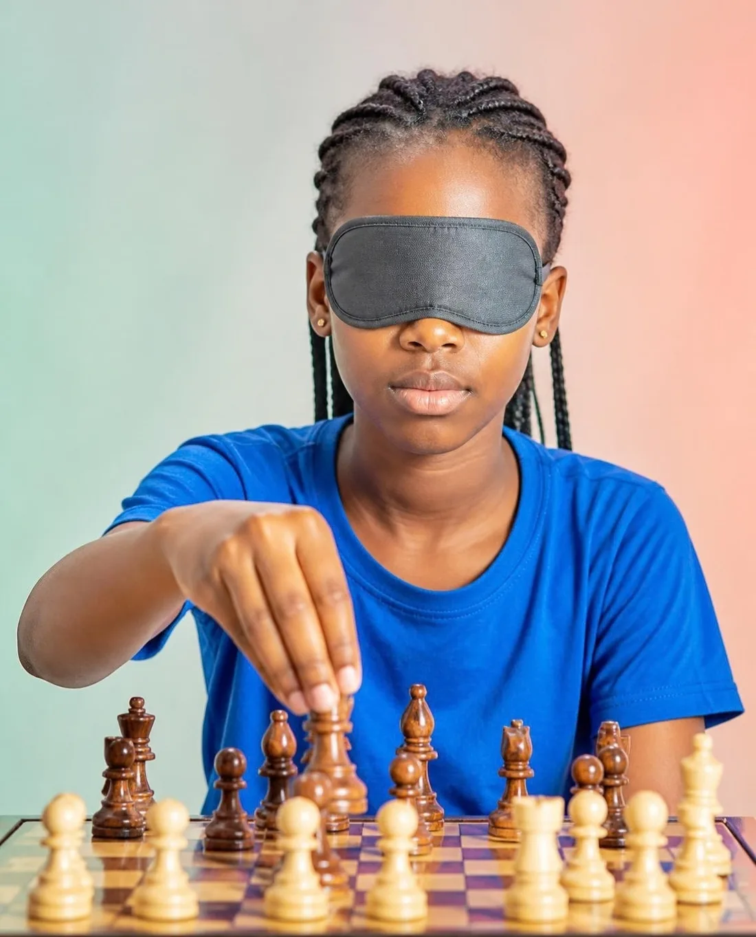 A girl in an eye mask moving a chess piece