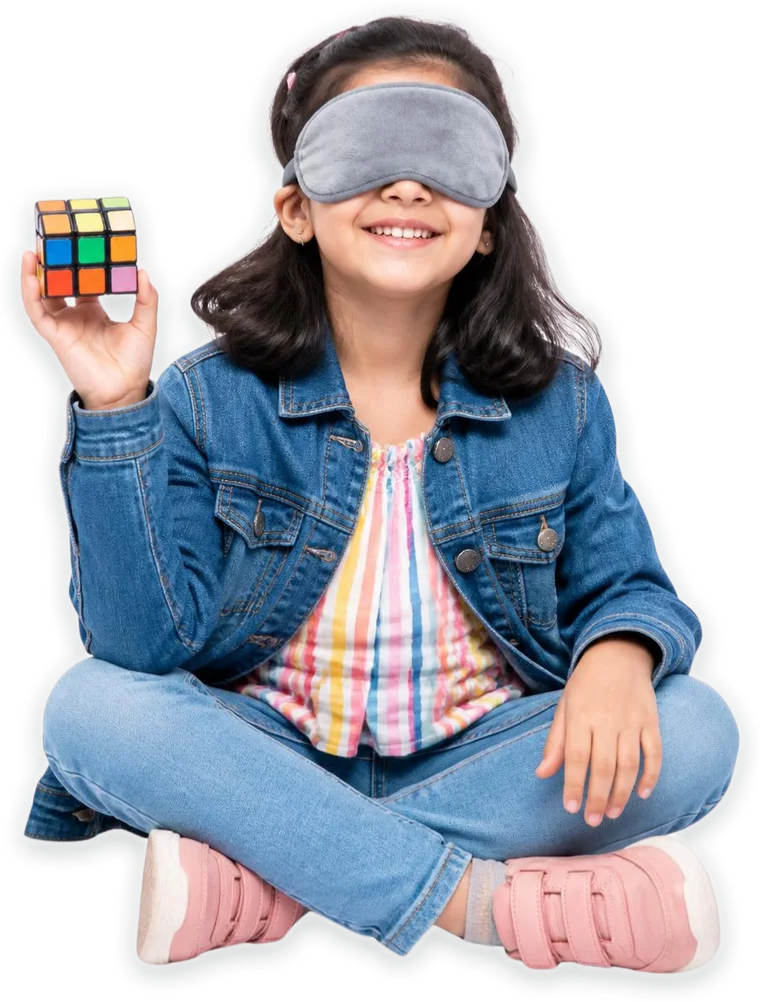 A smiling girl in an eye mask holding up a Rubik’s cube