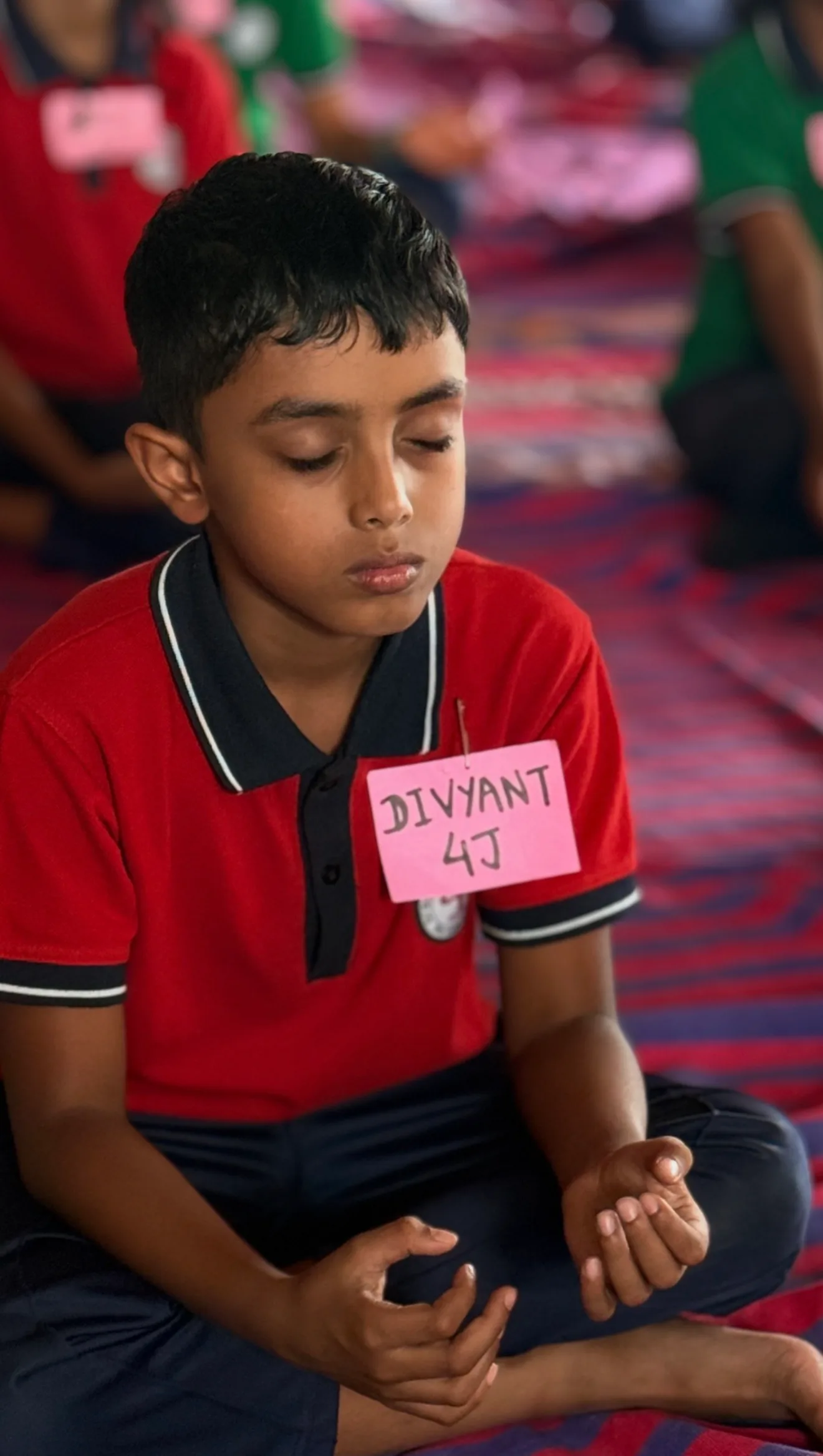 A boy in school uniform meditating with his eyes closed