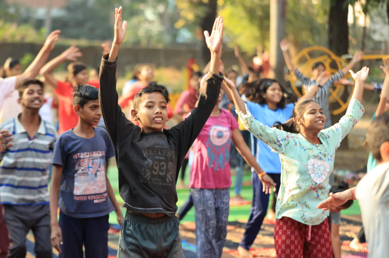 Children stretching their arms up at an outdoor session in Nagpur