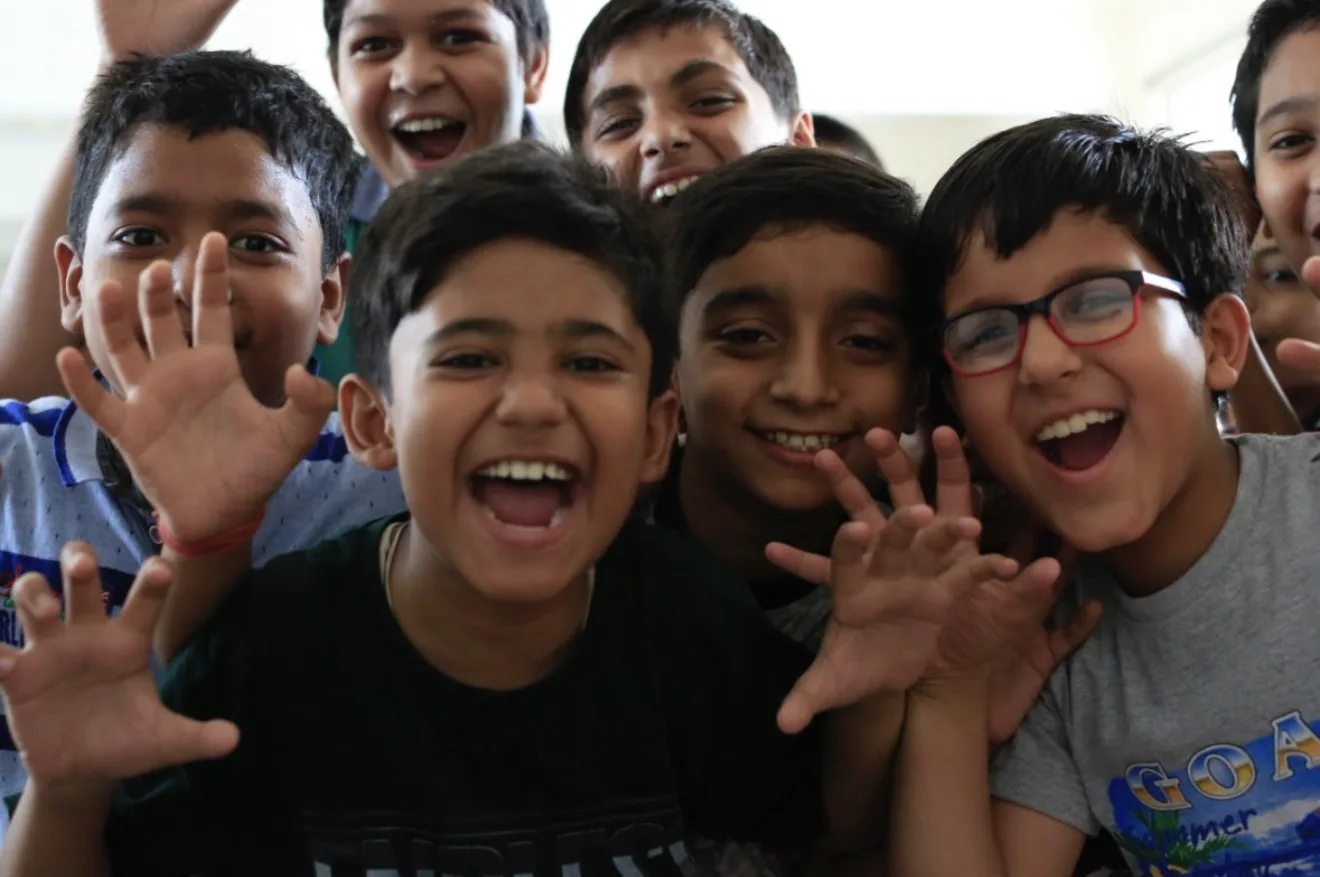 A group of laughing boys waving at the camera