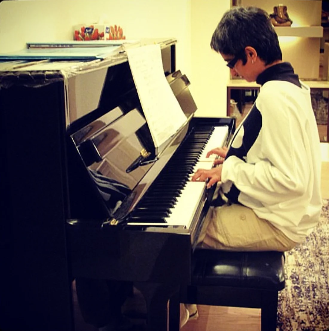 Shreya playing an upright piano at home