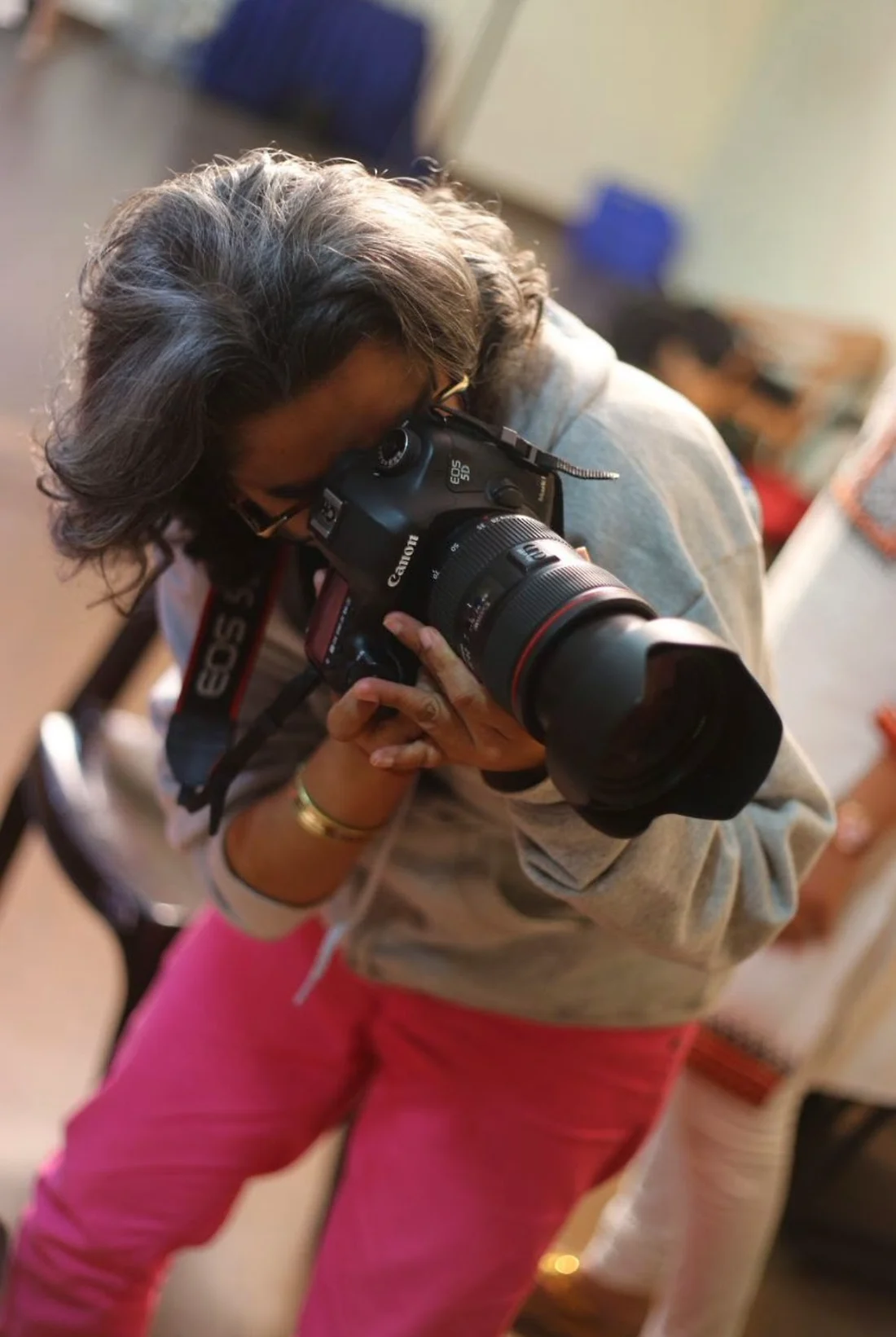 Shreya bending forward to take a photo with a Canon camera