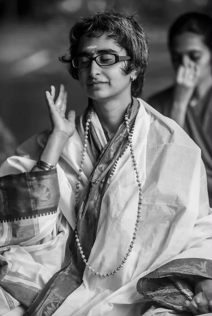 Shreya with eyes closed and a gentle smile, one hand raised in a mudra